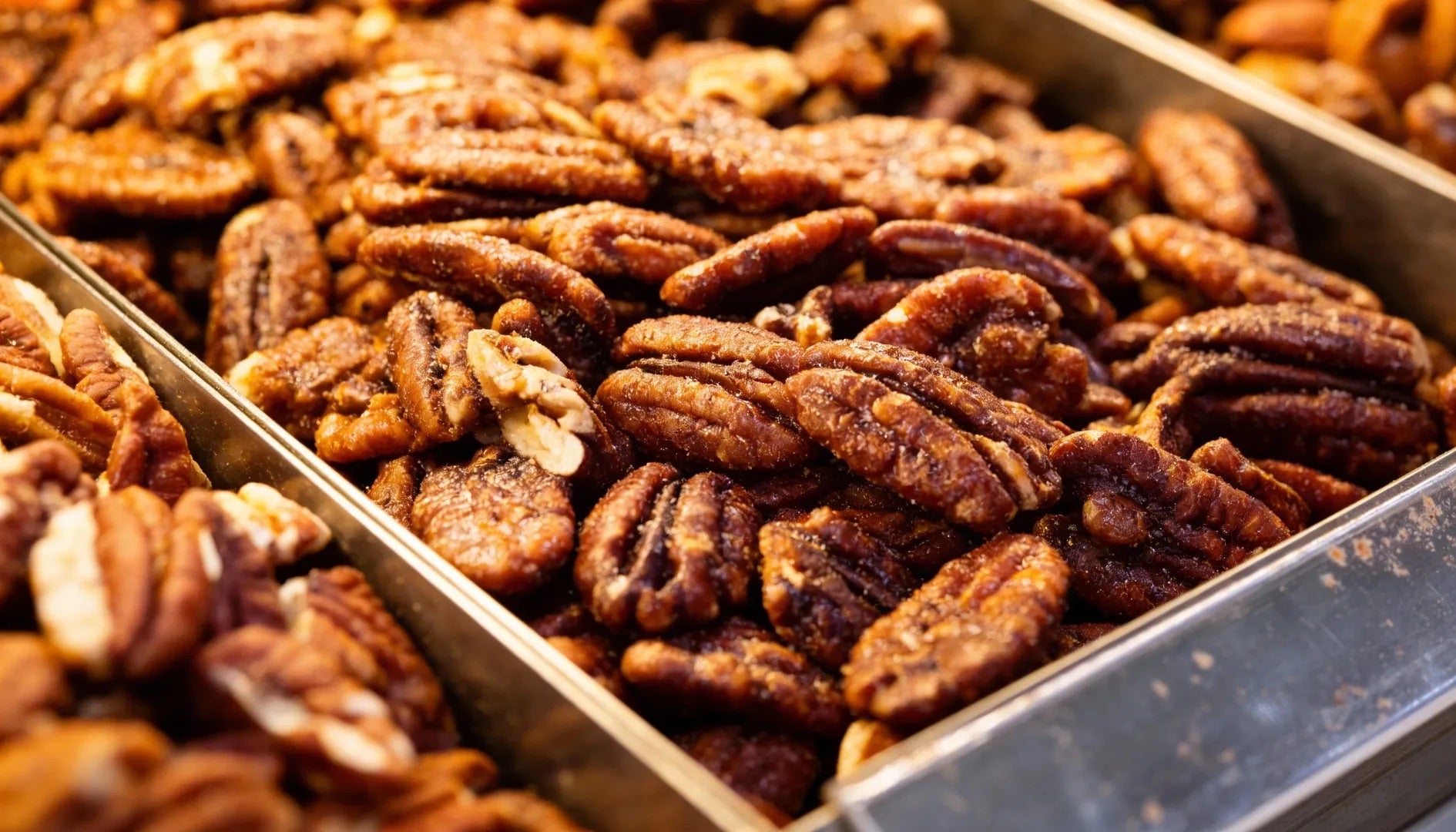 Seeds of Joy roasted pecans with a caramelised coating shown in a bulk display.